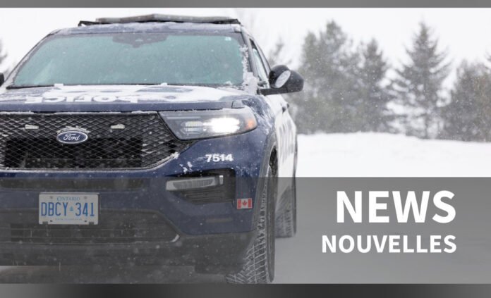 Front view of a blue Ford SUV with snow on the hood and windshield, parked outdoors in winter