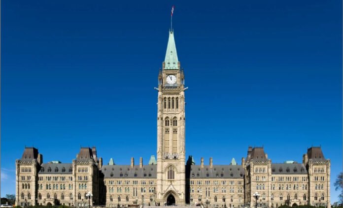 Parliament Hill in Ottawa, showing the Centre Block with the Peace Tower rising in the middle, under a clear blue sky