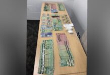 Barrie Police charged two after cocaine, cash found in traffic stop A table displaying seized evidence, including multiple stacks of Canadian currency in various denominations arranged in rows, alongside several small plastic bags containing a white powder believed to be drugs, photographed as part of a police seizure.