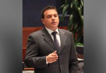 Former Toronto city councillor, Ontario MPP Giorgio Mammoliti dead at 64 Former MPP Giorgio Mammoliti in a dark suit, white shirt, and patterned tie speaks while gesturing with one hand, appearing to address a meeting or hearing. He is indoors, with a microphone and blurred plants visible in the background, suggesting a formal or institutional setting.