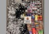 Hamilton man charged after alleged psilocybin sales at east-end storefront An overhead view of a large seizure display arranged on the floor, featuring numerous packaged substances of various sizes and colorful designs alongside many black and silver wrapped items. A sign reading “Hamilton Police Service” is placed in the center, indicating the items were confiscated by police.