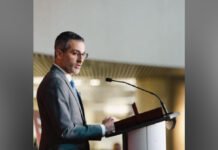 Ontario police watchdog announces provincewide police corruption probe Inspector general of Ontario Ryan Teschner in a dark suit and tie speaks at a podium with a microphone, shown in profile, addressing an audience in an indoor conference setting.