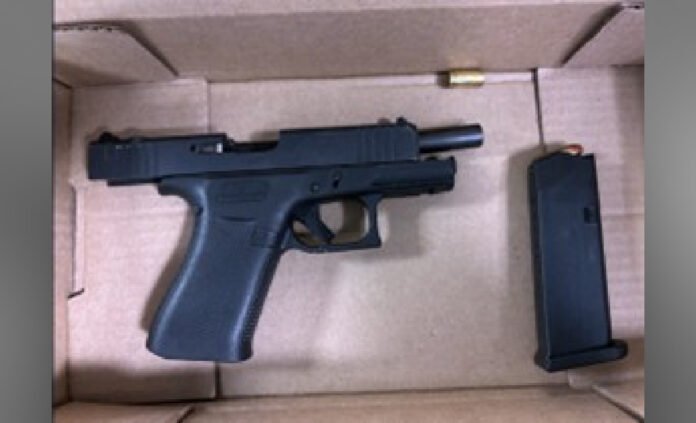  Police released image of a seized black handgun placed inside a cardboard evidence box, with a separate magazine lying beside it. 