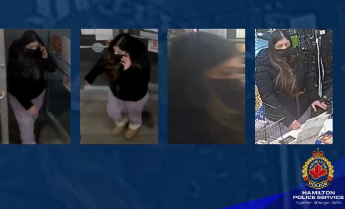 Distraction Theft Suspect A Hamilton Police Service image collage shows four surveillance photos of a female suspect linked to a distraction theft investigation. The woman appears to have long dark hair and is wearing a black face mask and a dark winter jacket. In two images she is holding a phone to her ear while walking indoors. In another image she appears blurred in motion. In the final image she is standing at a checkout counter with a shopping basket, looking down while handling items.