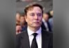 Ontario’s payout to Elon Musk over cancelled Starlink contract to remain secret image of Elon Musk wearing a black suit, white shirt, and black tie stands facing the camera with a neutral expression. The background is blurred with several people visible behind him, suggesting a public or formal event setting.
