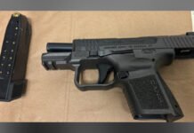 28-year-old faces multiple firearm charges following Toronto Police raid semi-automatic handgun placed on a flat surface with a detached magazine containing ammunition beside it.