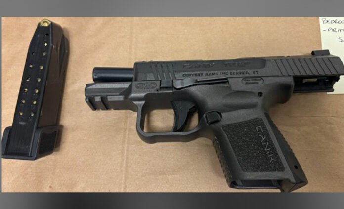 semi-automatic handgun placed on a flat surface with a detached magazine containing ammunition beside it.