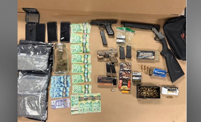 Items seized during a Toronto police firearm investigation displayed on a table, including two handguns, a sawed-off shotgun, multiple magazines, boxes and loose rounds of ammunition, several smartphones, Canadian currency, marijuana in a jar and plastic bags, and other related items.