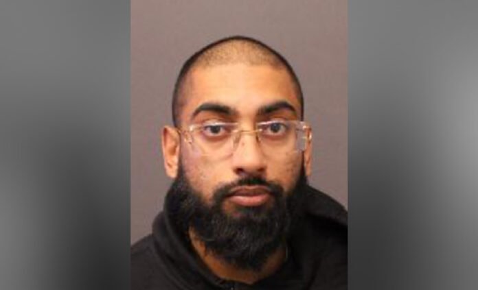 charged_in_hit_and_run Portrait of an adult man with a shaved head, full beard, and clear glasses, facing the camera against a plain background.