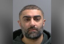 Peel Police issue warrant for fraud suspect after breach of release conditions Headshot of man with short dark hair and a full beard with some grey. He has a medium complexion and is wearing a dark hoodie while looking straight at the camera against a plain light background.