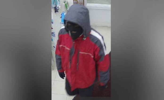 Survellance image of man released by police wearing a black ski mask, black gloves, a red jacket and black shoes with white soles