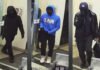 Armed robbery in Markham leaves three suspects at large Three masked individuals captured on surveillance camera inside a building entrance, each wearing dark clothing; one in a blue hoodie and white shoes, another carrying a bag, and all appearing to conceal their identities.