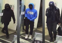 Armed robbery in Markham leaves three suspects at large Three masked individuals captured on surveillance camera inside a building entrance, each wearing dark clothing; one in a blue hoodie and white shoes, another carrying a bag, and all appearing to conceal their identities.